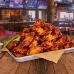 Crispy chicken wings served with dipping sauce and fresh garnish.